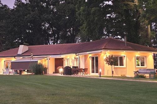 a yellow house with a lawn in front of it at Appartement Villa du Golf & SPA in Payerne