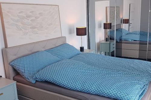 a bed with a blue comforter in a bedroom at Appartement Villa du Golf in Payerne