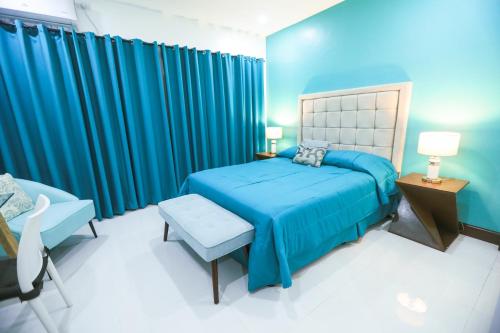 The Suites @ Bellavista في Isabel: غرفة نوم زرقاء مع سرير وكرسي