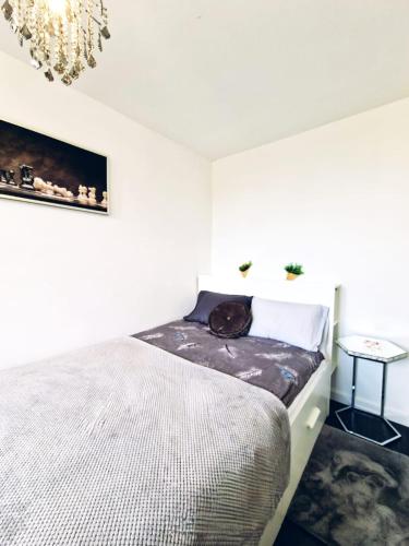 a white bedroom with a bed and a chandelier at Apartament nad Pisą in Pisz