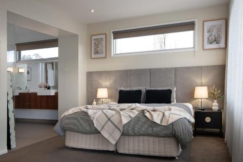 a bedroom with a large bed with two windows at Bilsons Landing East in Daylesford