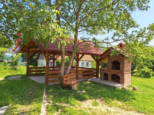 a wooden pavilion with a tree in a field at Kokotova hiža in Gornja Konjšćina