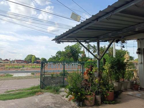 a pergola with plants in pots next to a fence at YaiJaew House in Sukhothai