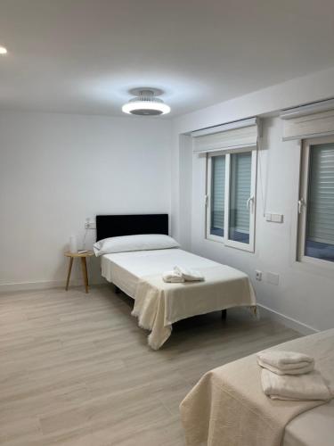 Apartamento Arena Benidorm في بنيدورم: غرفة بيضاء بسريرين ونافذة