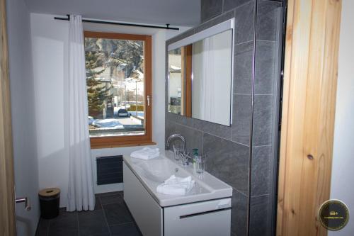 baño con lavabo, espejo y ventana en Ferienwohnungen Haus Alte Bäckerei en Randa