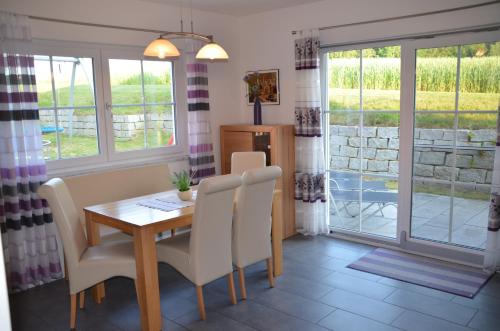 a dining room with a wooden table and white chairs at Ferienhäuser Schneeberger 