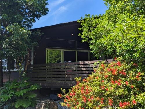 a black house with some flowers in front of it at プライベート温泉付き隠れ家　Shankara Lodge ~stay & retreat~ in Kirishima