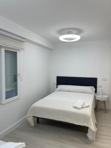 a white bedroom with a bed and a window at Apartamento Arena Benidorm in Benidorm