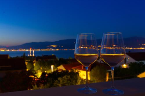 two glasses of wine sitting on a balcony at night at ꕥ Apartments Residence SUNCE Supetar, Family choice - cozy base to stay and explore island Brac FREE PARKING in Supetar