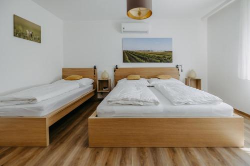 two beds in a room with white walls and wooden floors at Ferienwohnung Illy in Illmitz