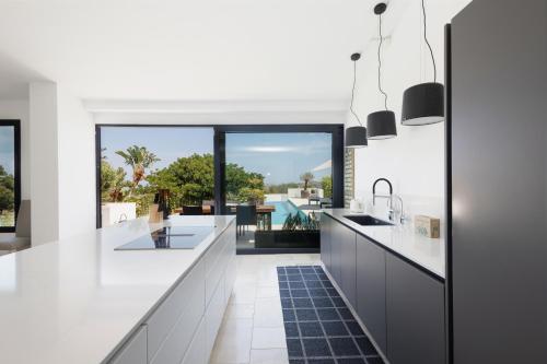 Spectacular villa, with infinity pool and sea views, la Mairena, Elviria, Marbella في أُوخين: مطبخ به كونترات بيضاء ونافذة كبيرة
