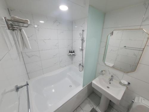 a white bathroom with a tub and a sink at NO25 Hotel Ansan in Ansan