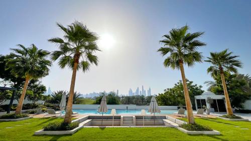 a pool with palm trees and a city in the background at Villa Botanica-Exclusive 8-Bedroom Villa by Luxury Explorers' Collection in Dubai