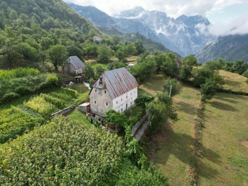 an aerial view of a house in a field with mountains at Marash Rrgalla Guesthouse in Theth