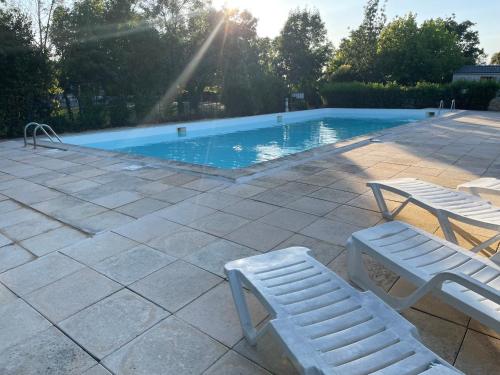 a swimming pool with two white chairs next to it at CAMPING ANIMAL KING in Esnandes