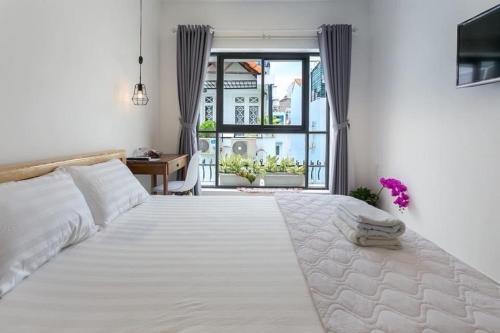 a bedroom with a large white bed and a window at Vika Homestay in Ho Chi Minh City