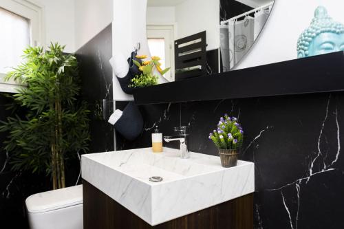 a bathroom with a white sink and a black wall at Italstay - Disciplini Duplex - 10 min dal Duomo in Milan