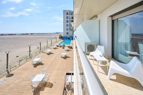 een balkon met witte tafels en stoelen en het strand bij CAELIA Residence ap 2 camere in Mamaia