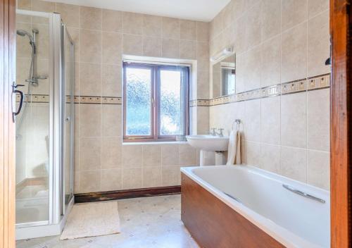 a bathroom with a tub and a sink and a bath tub at Danycrug Barn in Brecon