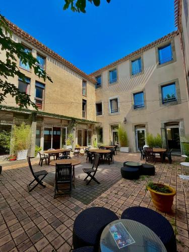 un patio avec des tables et des chaises en face d'un bâtiment dans l'établissement Hostel Coeur de cité, à Carcassonne
