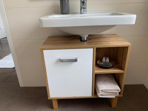 a bathroom with a sink and a white cabinet under a sink at Apartmenthaus Villa Lindenbühl in Mühlhausen