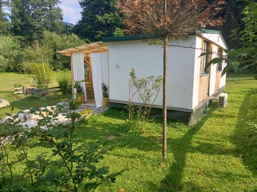 a small white shed in a yard with a tree at Edenski vrt in Ivančna Gorica