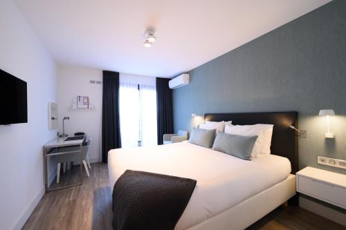 a bedroom with a large white bed and a desk at Van der Valk Hotel Saint-Aygulf in Saint-Aygulf