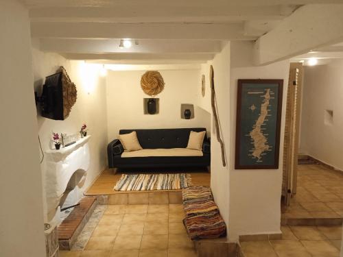 una sala de estar con un sofá negro en una habitación en Afiartis Almira Cottage en Kárpatos