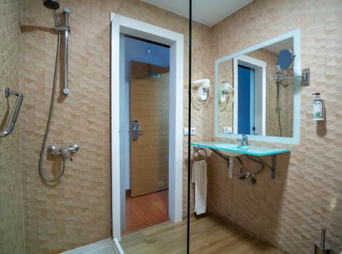 Un baño con ducha, lavabo y espejo. en Hotel Familia Conde, en Huelva