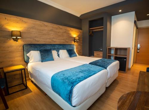 Un dormitorio con una cama grande con una manta azul. en Hotel Familia Conde, en Huelva