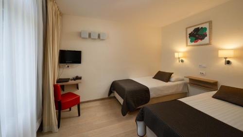 a hotel room with two beds and a red chair at Hotel Bellevue in Plitvička Jezera