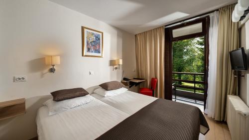 une chambre d'hôtel avec un lit et une fenêtre dans l'établissement Hotel Bellevue, aux lacs de Plitvice