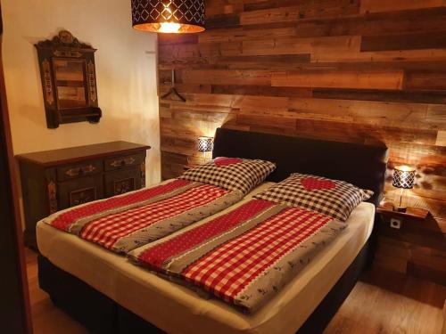 uma cama num quarto com uma parede de madeira em Schwarzeck34 em Bachwinkl