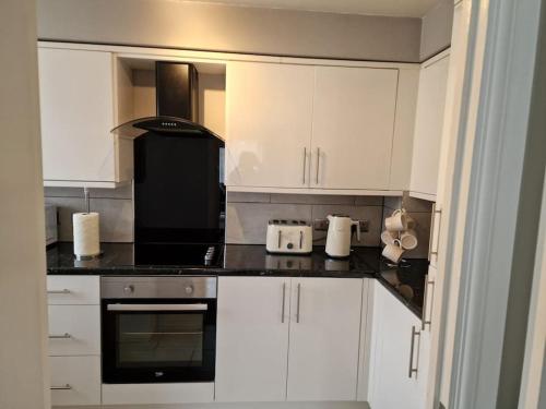 a kitchen with white cabinets and black counter tops at Modern two bedroom flat in North Stifford