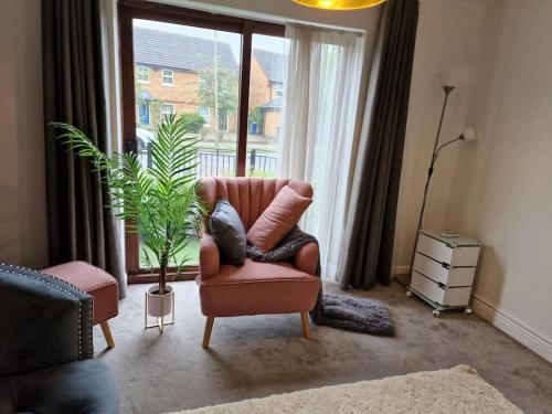 a living room with a chair and a plant and a window at Modern two bedroom flat in North Stifford