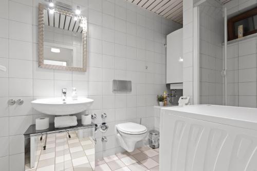ein weißes Badezimmer mit einem Waschbecken, einem WC und einer Badewanne in der Unterkunft Flatista Homes - Garden House in München