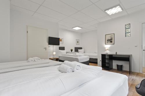 Dieses weiße Zimmer verfügt über 2 Betten und einen TV. in der Unterkunft Flatista Homes - Garden House in München