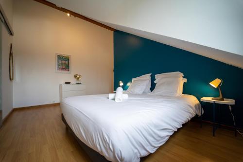 a bedroom with a large white bed with a blue wall at appartement proche lac d'Annecy in Faverges