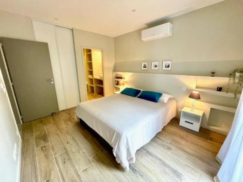 une chambre avec un grand lit blanc avec des oreillers bleus dans l'établissement La Pinede 350m de la Plage, à Les Sables-dʼOlonne