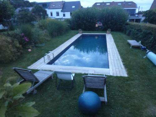 a swimming pool with two chairs and a table at Beatrice's gardens in Nivelles