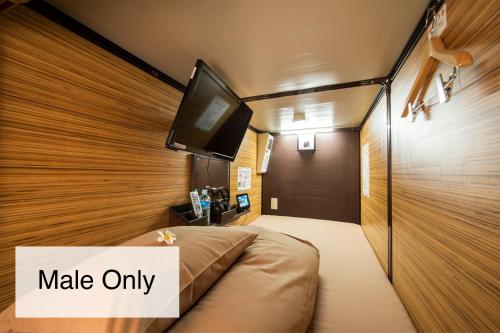 a bedroom with a bed with a tv on the wall at Anshin Oyado Shinjuku Ekimaeten in Tokyo