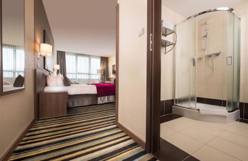 a hotel room with a shower and a bed at Leonardo Royal Hotel Warsaw in Warsaw