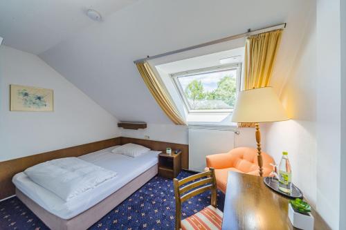 a bedroom with a bed and a desk and a window at Hotel Franken in Forchheim