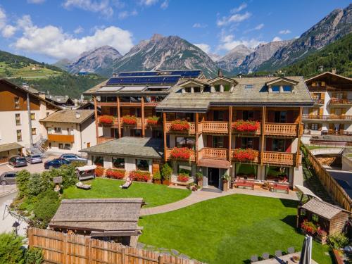 a large building with a green yard in front of mountains at La Genzianella Bormio in Bormio