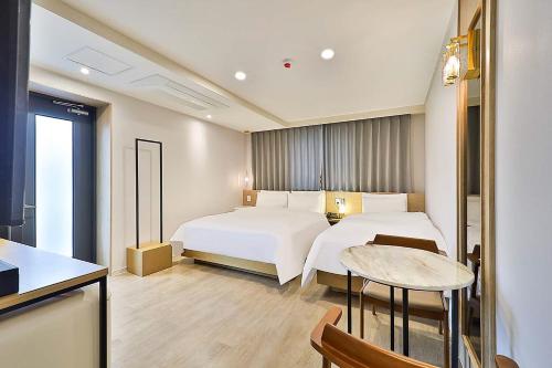 a hotel room with two beds and a table at Hotel Rubato Ulsan Jung-gu Haksung in Ulsan