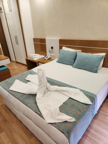 a large bed with white sheets and blue pillows at Esperanza Hotel in Antalya