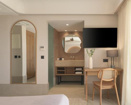 a bedroom with a desk with a tv and a mirror at Paralos Venus Suites Adults Only in Hersonissos