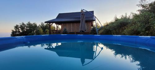 a swimming pool with a house in the background at Domki Drewniane Królewska Góra in Czarnorzeki