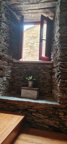 une fenêtre dans un mur de briques avec une plante en pot dans l'établissement ALBERGUE CASTELOS, à Lorenzana