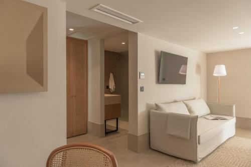 a living room with a couch and a television at Paralos Venus Suites Adults Only in Hersonissos